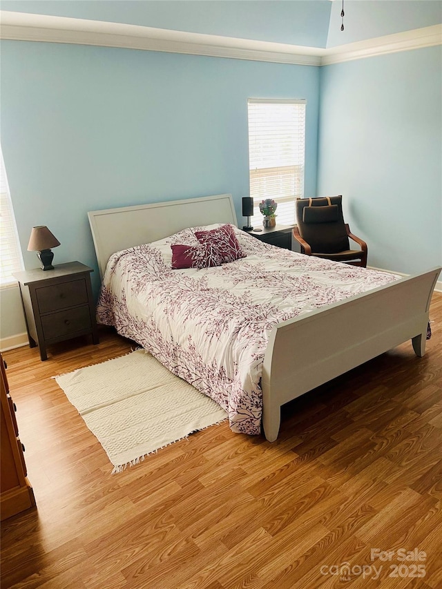 bedroom featuring wood finished floors and crown molding