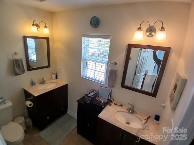 bathroom featuring toilet, tile patterned flooring, two vanities, and a sink