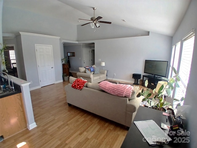 living room featuring lofted ceiling, ceiling fan, baseboards, and light wood-style floors