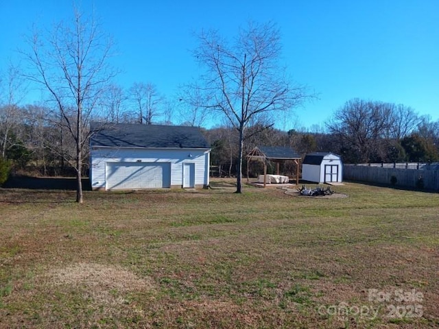 view of yard with an outbuilding, fence, a detached garage, and a storage unit