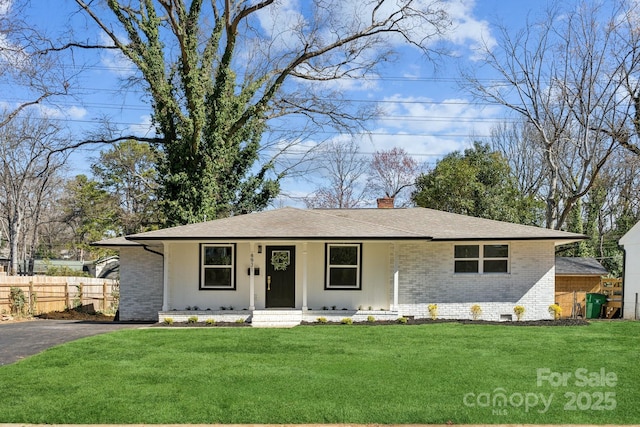 view of front of house with brick siding, fence, crawl space, a chimney, and a front yard