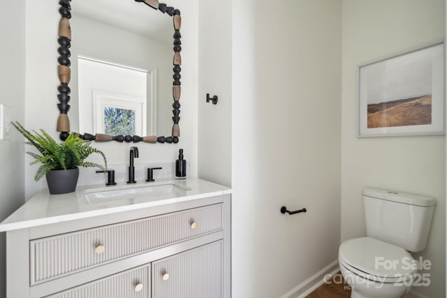 half bath featuring toilet, baseboards, and vanity