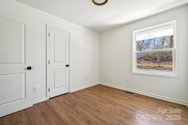 unfurnished bedroom with visible vents, baseboards, and wood finished floors