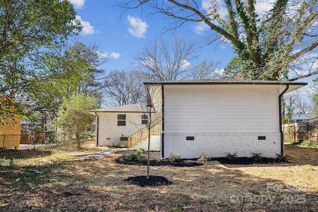 view of home's exterior featuring crawl space and fence