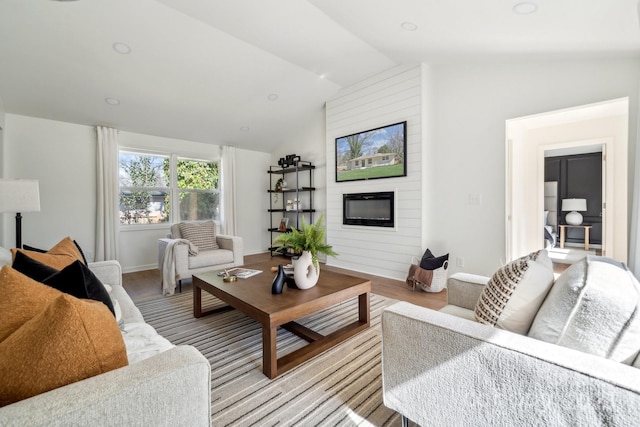 living room with lofted ceiling, a large fireplace, baseboards, and light wood finished floors