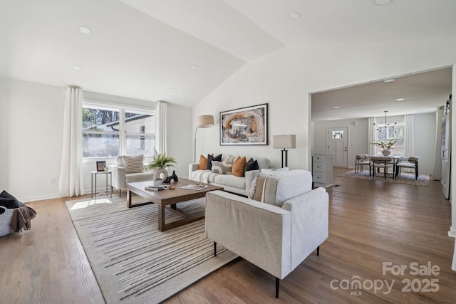 living area featuring lofted ceiling, baseboards, and wood finished floors