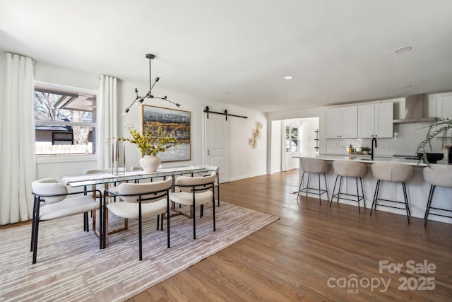 dining room with recessed lighting, light wood finished floors, and a barn door