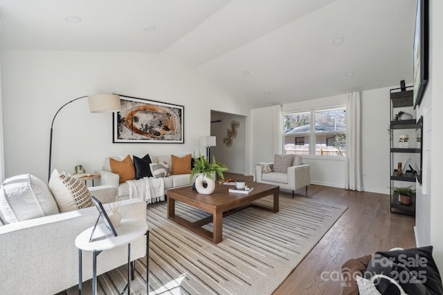 living area with vaulted ceiling, baseboards, and wood finished floors