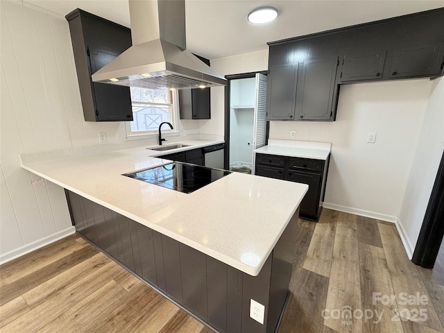 kitchen featuring island range hood, dishwasher, a peninsula, black electric stovetop, and a sink