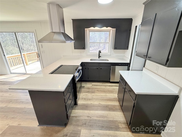 kitchen featuring electric range, a peninsula, a sink, wall chimney range hood, and stainless steel dishwasher