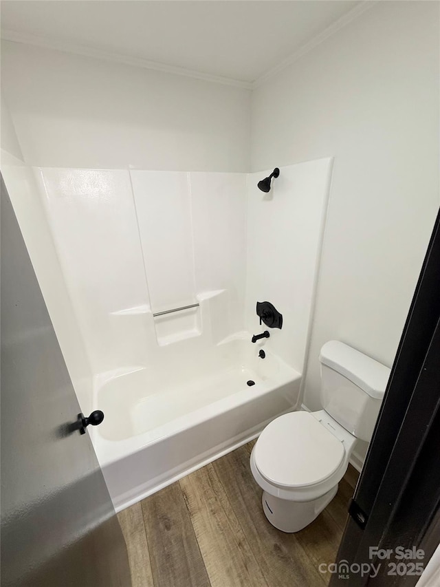 bathroom with ornamental molding, shower / bathing tub combination, toilet, and wood finished floors