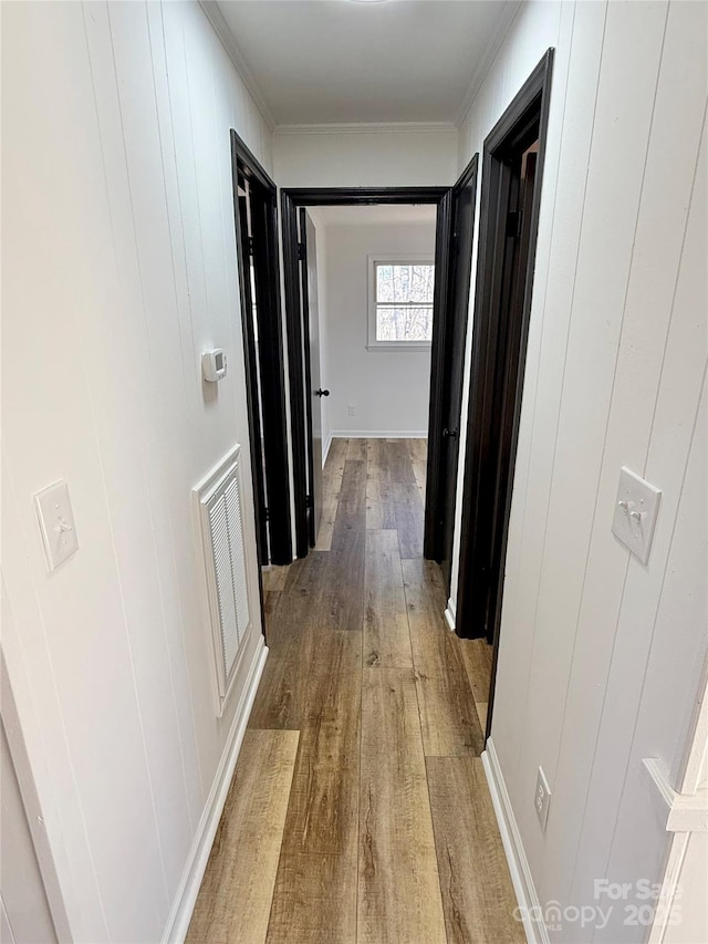 hallway with wood finished floors, visible vents, and crown molding