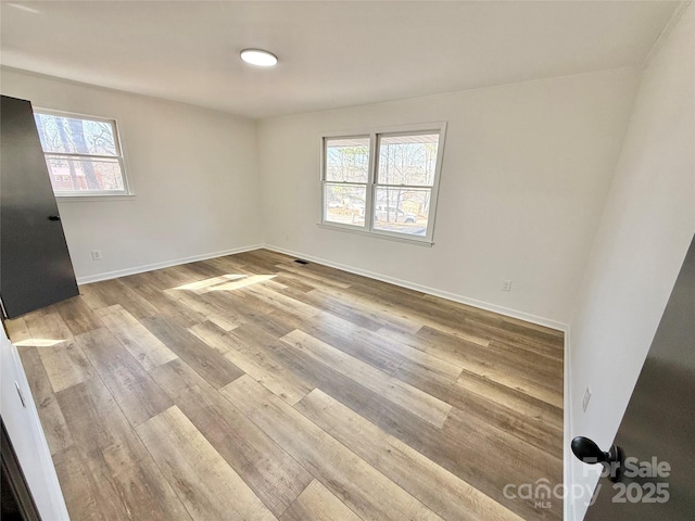 empty room with baseboards and wood finished floors