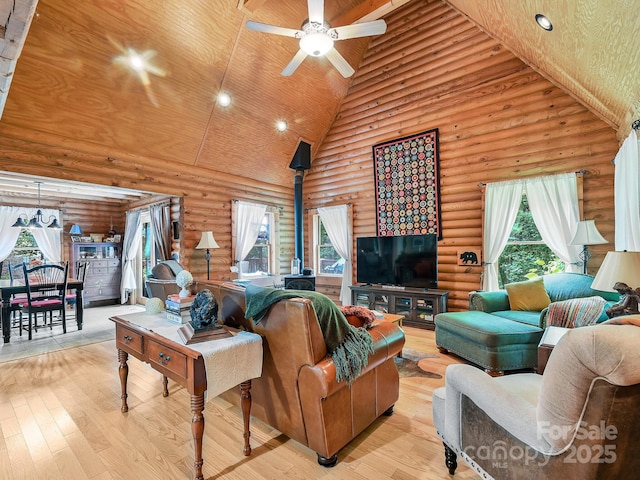 living room featuring a wood stove, light wood-type flooring, high vaulted ceiling, and a ceiling fan