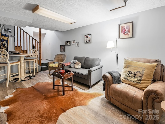 living area with stairs, a textured ceiling, and wood finished floors