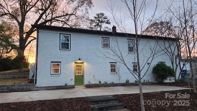 621 Watts St NE, Valdese, NC 28690 - view of front of home featuring a chimney, brick siding, and a patio area