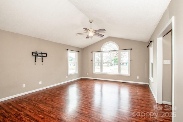 empty room featuring a barn door, baseboards, a ceiling fan, lofted ceiling, and wood finished floors