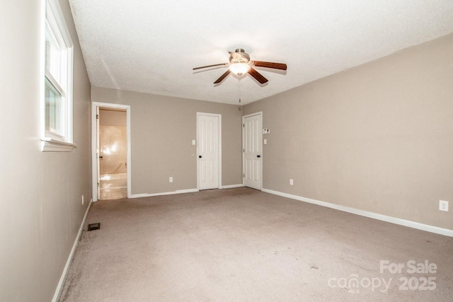 carpeted empty room featuring a ceiling fan, visible vents, and baseboards