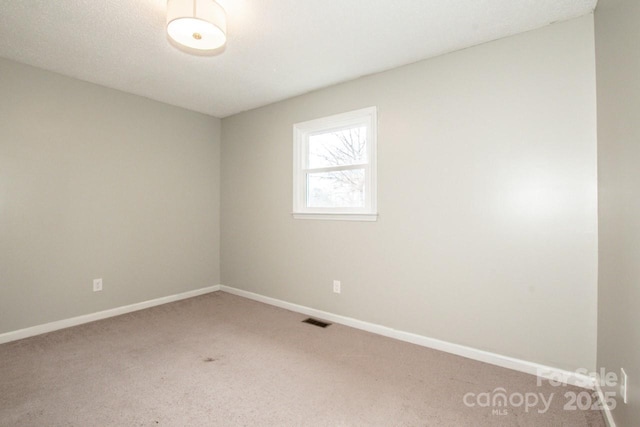 empty room featuring baseboards, visible vents, and carpet flooring