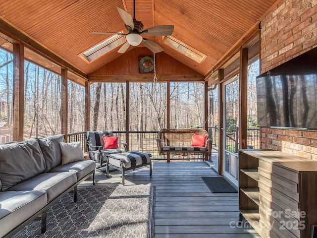 unfurnished sunroom featuring wood ceiling, vaulted ceiling with skylight, and a ceiling fan