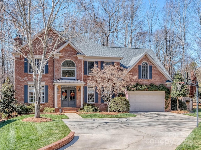 view of front of house featuring driveway, a chimney, a front lawn, and brick siding