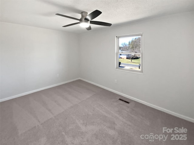 carpeted spare room featuring a ceiling fan, visible vents, a textured ceiling, and baseboards