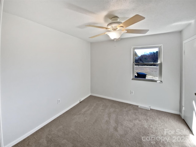 unfurnished room with a ceiling fan, light colored carpet, visible vents, and baseboards