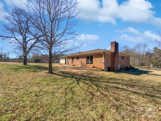 exterior space featuring a chimney, a lawn, and brick siding