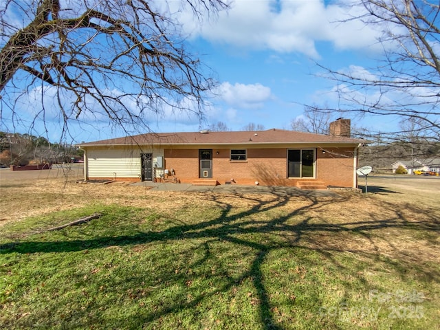 back of property with a yard, brick siding, and a chimney