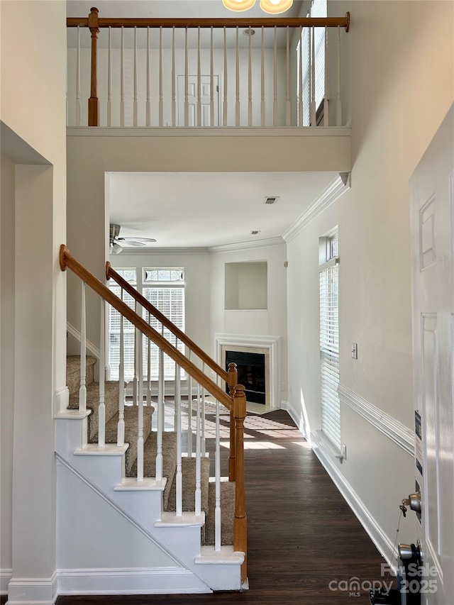 staircase with a fireplace, wood finished floors, a wealth of natural light, and baseboards