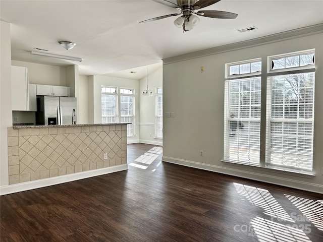 unfurnished living room featuring ceiling fan, dark wood-type flooring, visible vents, baseboards, and crown molding