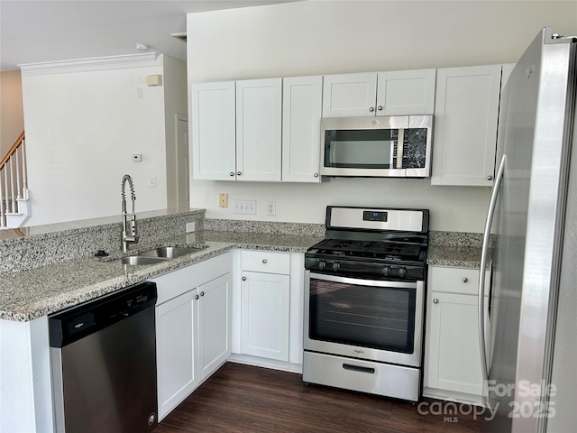 kitchen featuring appliances with stainless steel finishes, white cabinets, a sink, and light stone countertops