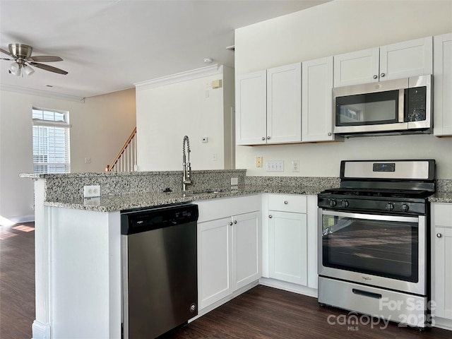 kitchen featuring stainless steel appliances, stone countertops, a peninsula, and a sink