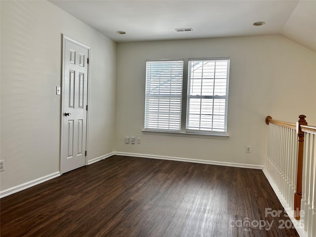 empty room featuring lofted ceiling, baseboards, visible vents, and wood finished floors