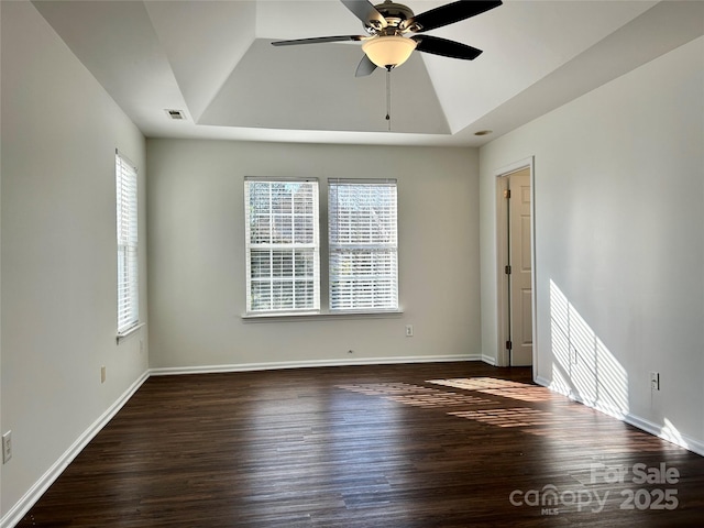 spare room with baseboards, visible vents, ceiling fan, wood finished floors, and a tray ceiling