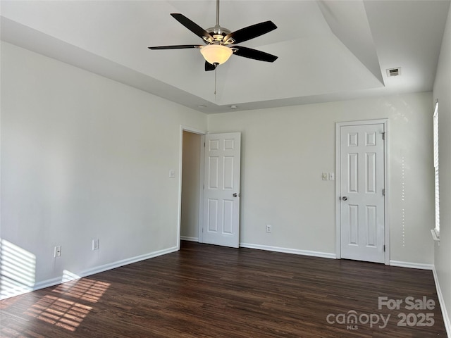 interior space with a raised ceiling, baseboards, visible vents, and dark wood-style flooring