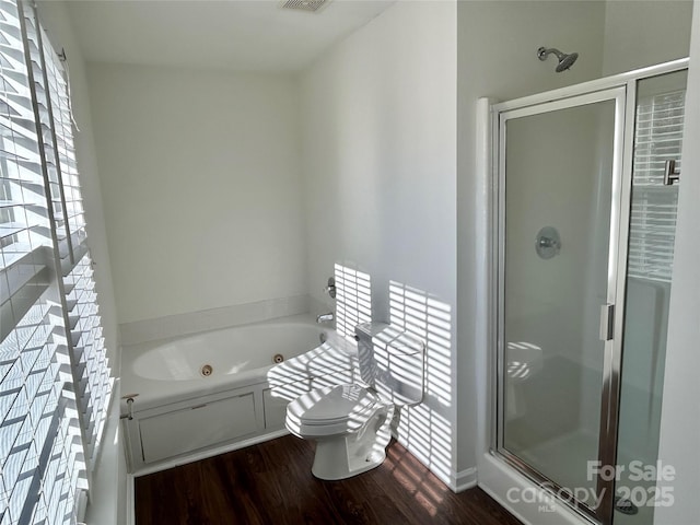 full bathroom featuring a stall shower, wood finished floors, toilet, and a jetted tub