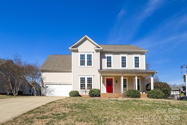 view of front of house with a standing seam roof, a porch, concrete driveway, a front lawn, and metal roof