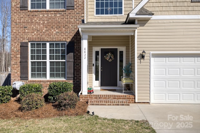 property entrance with an attached garage and brick siding