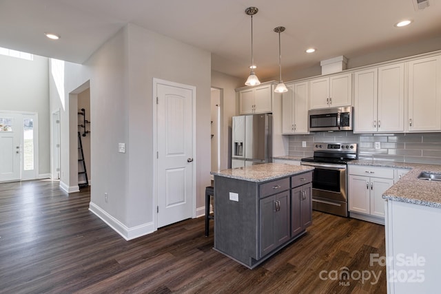 kitchen featuring white cabinets, tasteful backsplash, stainless steel appliances, and dark wood finished floors