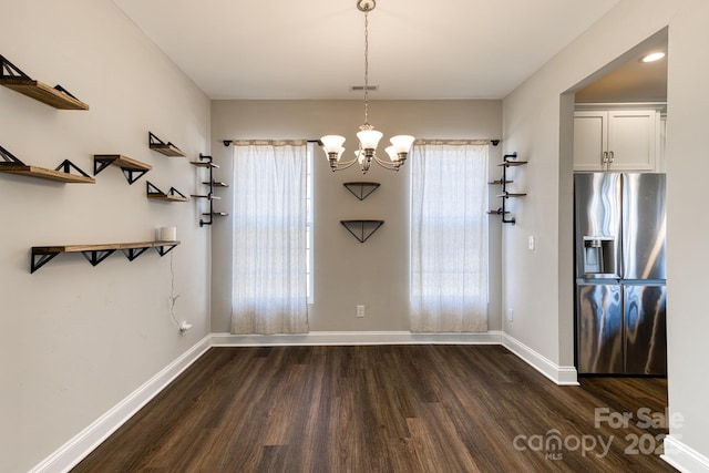 unfurnished dining area with a notable chandelier, baseboards, and dark wood-type flooring