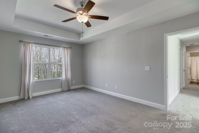 spare room with baseboards, visible vents, and a raised ceiling