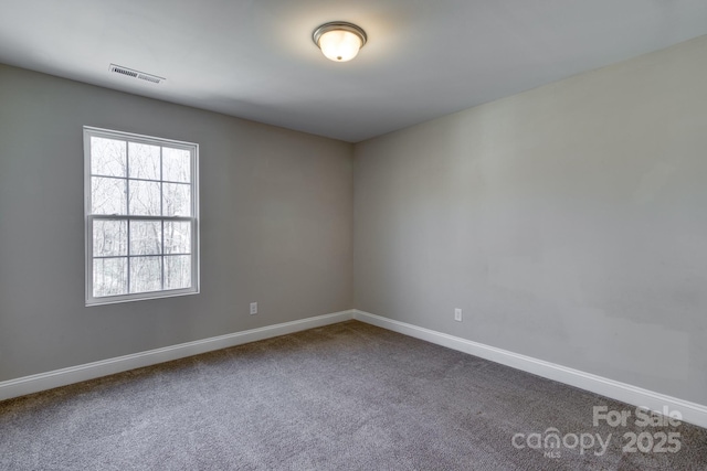 empty room featuring dark carpet, visible vents, and baseboards