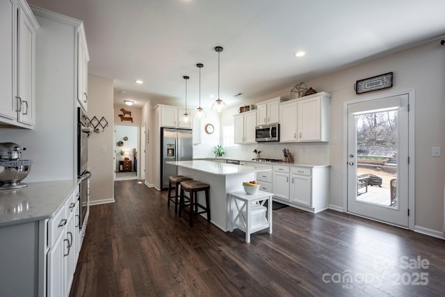 kitchen featuring white cabinets, a kitchen island, stainless steel appliances, and a kitchen breakfast bar