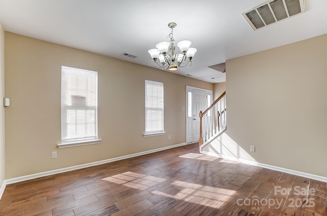 unfurnished room featuring visible vents, a chandelier, and wood finished floors