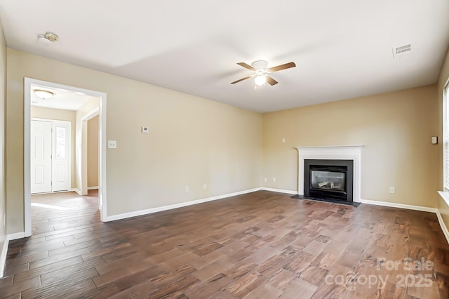 unfurnished living room featuring ceiling fan, a fireplace with flush hearth, wood finished floors, visible vents, and baseboards