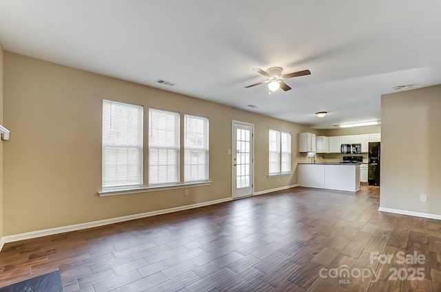 unfurnished living room featuring ceiling fan, dark wood-style flooring, visible vents, and baseboards