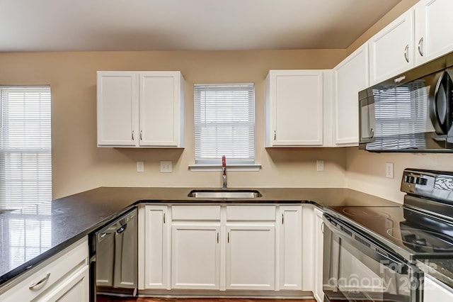 kitchen featuring dark countertops, a sink, black appliances, white cabinetry, and a wealth of natural light