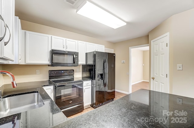 kitchen featuring wood finished floors, a sink, white cabinets, black appliances, and dark stone countertops