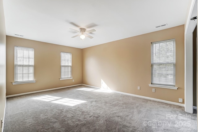 carpeted spare room featuring ceiling fan, visible vents, and baseboards